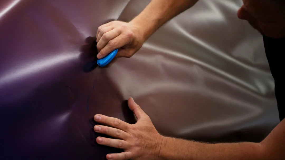 Un homme peint un tissu violet avec un pinceau bleu, utilisant de la nano céramique pour une finition lisse.